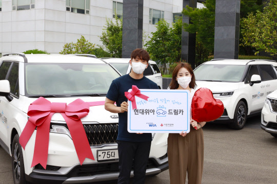현대위아 직원들이 22일 경상남도 창원시 성산구 현대위아 본사에서 지역 복지기관에 선물할 '현대위아 드림카'와 기념사진을 찍고 있다. <현대위아 제공>